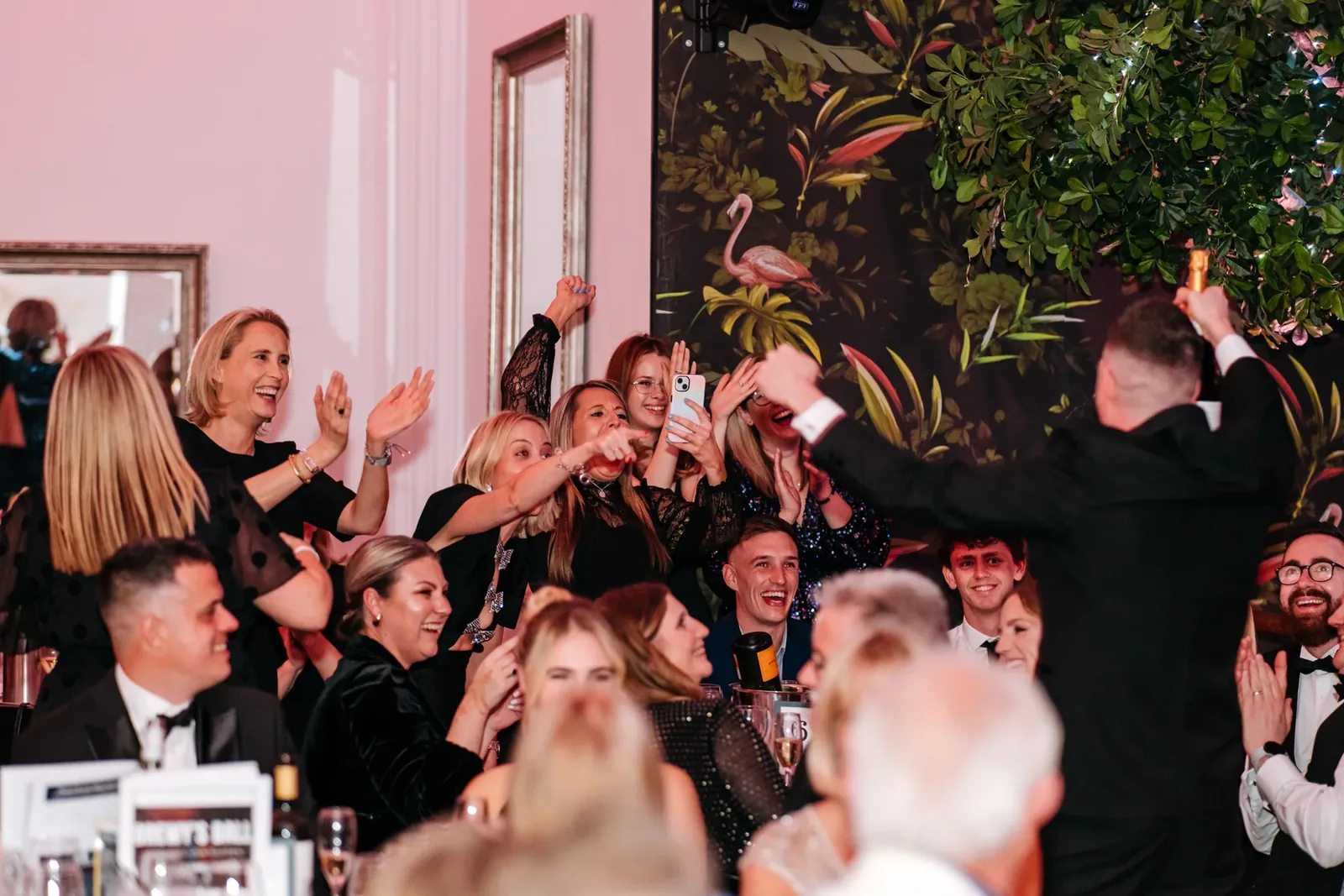Guests applauding and cheering around a table at a black tie dinner at The Grand