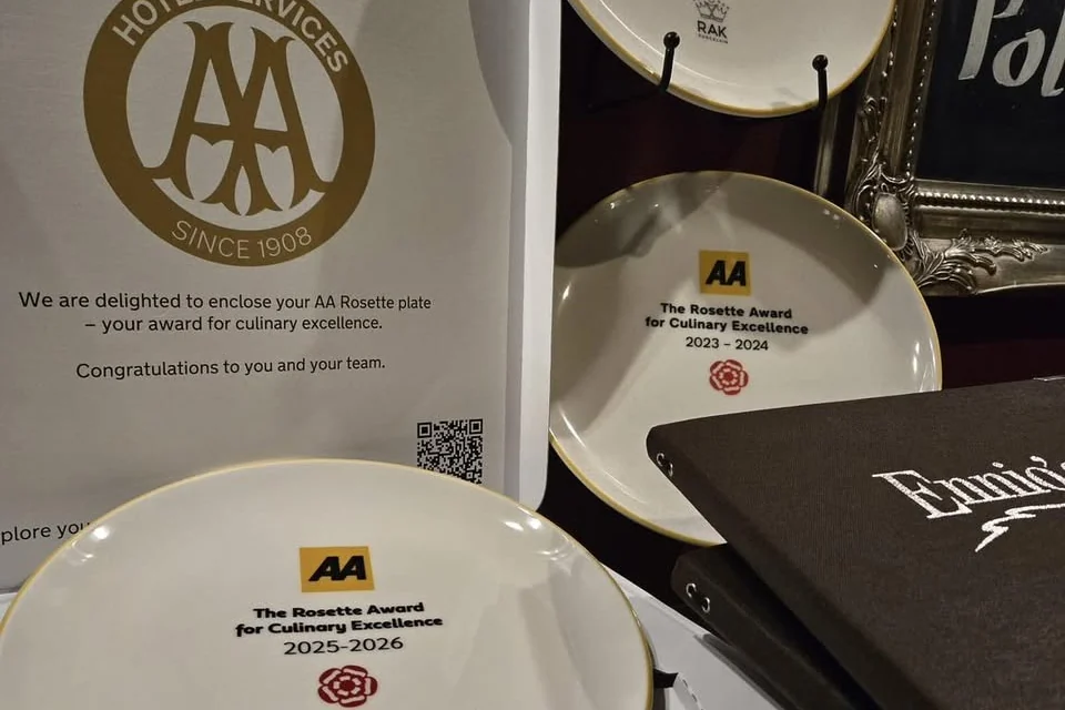 The 2025 to 2026 AA Rosette plate at Ennios, with the 2023-24 and 2024-25 plates and the AA letter behind it