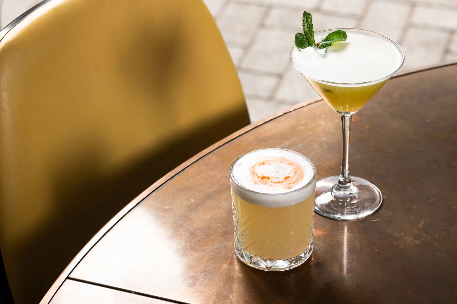 Two cocktails on a copper table in the daylight at Banana Wharf